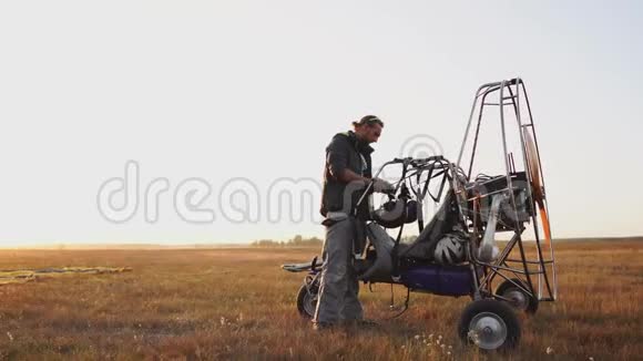 汽车滑翔伞在日落时分用木制螺旋桨站在田野里飞行员伸出降落伞视频的预览图