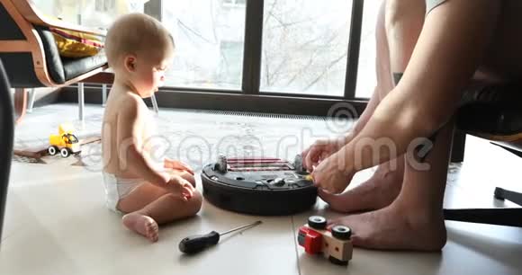 小男孩和爸爸在地板上修理机器人视频的预览图