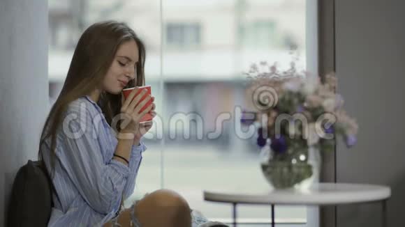 年轻女孩喜欢坐在窗台上喝咖啡视频的预览图