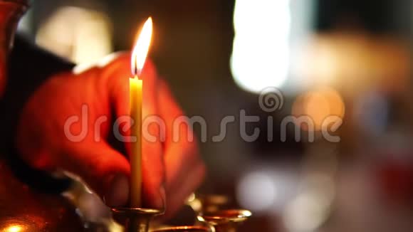 在基督教东正教教堂的烛台上人类的手特写放了一支蜡烛视频的预览图