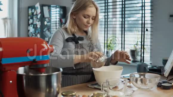 年轻漂亮的女人在厨房做饭在厨房秤里称可可然后打开搅拌机视频的预览图