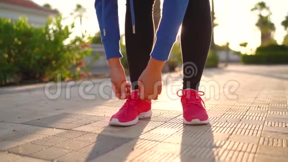 在日落时分女人系鞋带沿着棕榈大道奔跑慢动作视频的预览图