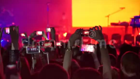 在摇滚音乐会上的人群聚会上人们手里拿着许多带有数码显示器的照相机视频的预览图