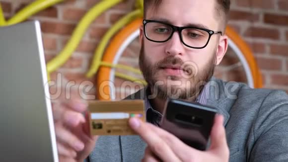 网上银行与智能手机一个留着胡子的时髦的现代年轻人用银行信用卡在视频的预览图