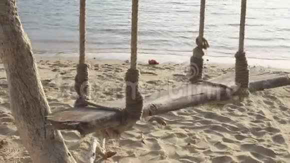 木秋千挂在树下沙滩和海边视频的预览图