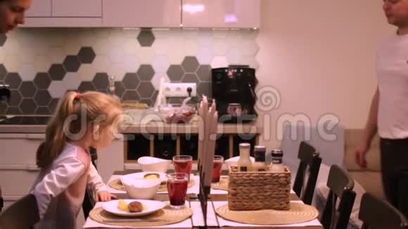 家庭晚餐妈妈爸爸和女儿坐在桌边吃晚饭视频的预览图