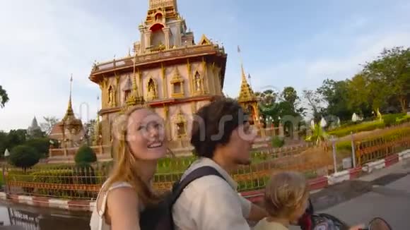 一家人骑着摩托车在普吉的瓦查龙佛教寺庙前自拍的慢镜头视频的预览图