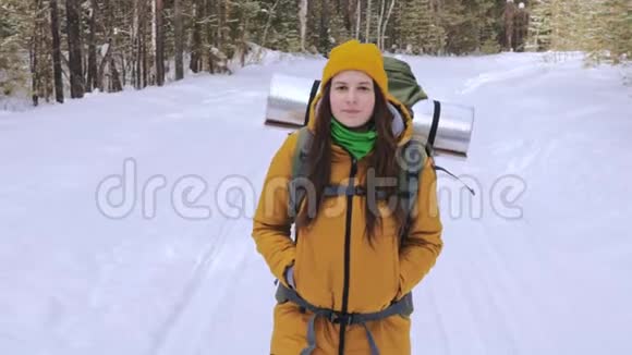 女游客走在一条冬天的森林路上肩上背着一个背包视频的预览图