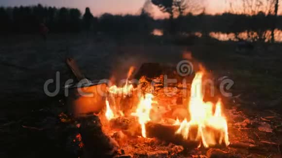 食物是在锅中的篝火上煮熟的用树枝打开盖子在河岸露营的人视频的预览图