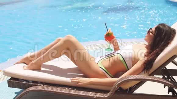 穿着比基尼的年轻女人躺在阳光下靠近蓝色的大海视频的预览图