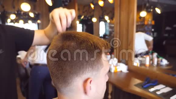 头发造型过程男理发师在理发店给他的男客户梳头慢动作关闭视频的预览图