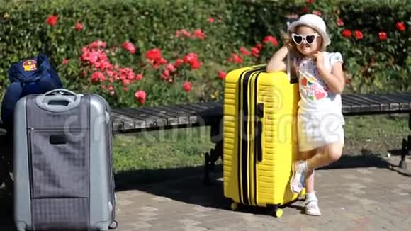 带黄色大手提箱的儿童游客等待旅行的小女孩视频的预览图
