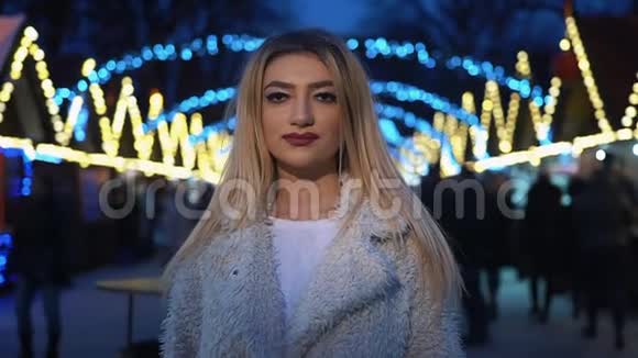 漂亮的变性女人站在城市广场的圣诞装饰中直视着镜头视频的预览图