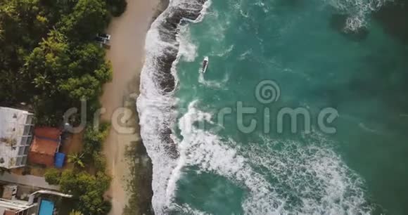 空中飞人无人机拍摄田园诗般的异国海岸与小船泡沫白色的撞击波和度假屋视频的预览图