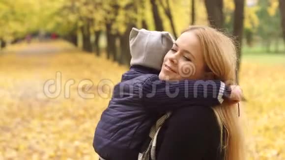 妈妈在秋天公园里轻轻地拥抱她的儿子视频的预览图