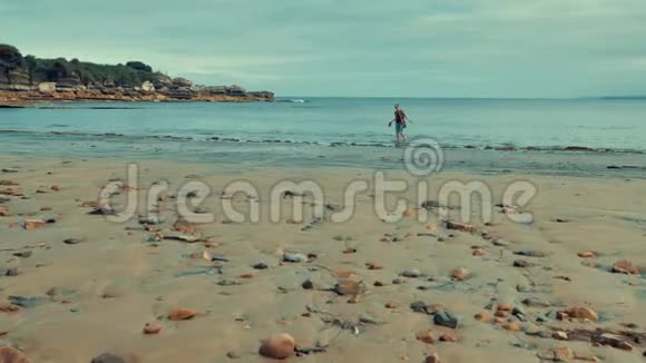 年轻女性独自一人在荒凉的大西洋海岸带着北欧风格的自然环境的岩石和沙子视频的预览图