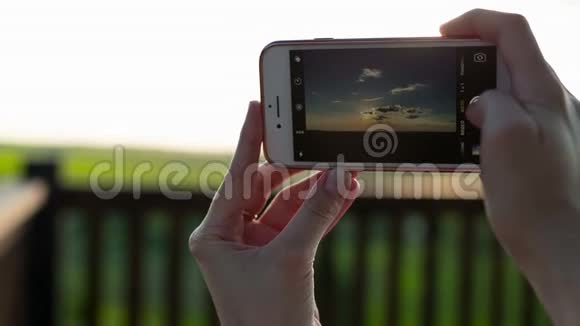 女性使用智能手机拍摄日落照片的特写镜头视频的预览图