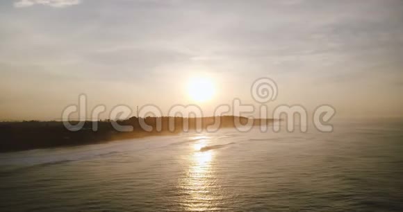 在美丽的夕阳海洋上空飞翔的无人机令人惊叹的空中全景夕阳反射海浪到达海岸视频的预览图
