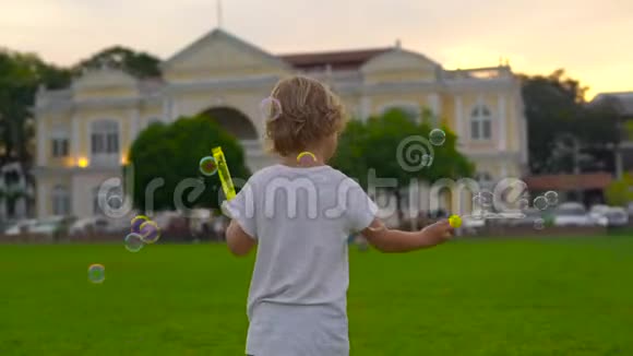 一个小男孩在乔治敦市政厅前的广场上玩泡泡鼓风机的慢镜头视频的预览图