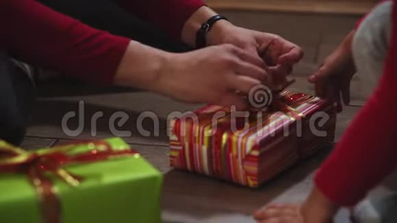 特写女人和女孩的手用盒子包装礼物以圣诞节和新年的颜色视频的预览图