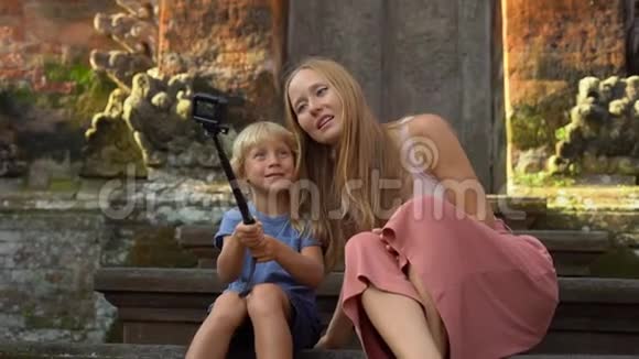 一位美丽的年轻女子和她的小儿子在楼梯上用动作台动作摄像机自拍的慢镜头视频的预览图