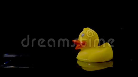 橡胶鸭在黑色背景下漂浮在水面上视频的预览图