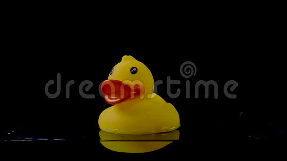 橡胶鸭在黑色背景下漂浮在水面上视频的预览图