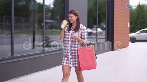 一个漂亮的女孩带着包裹去购物手里拿着一杯咖啡慢动作视频的预览图