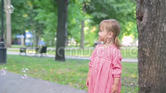 穿着粉红色衣服的小女孩捕捉肥皂泡慢动作视频的预览图