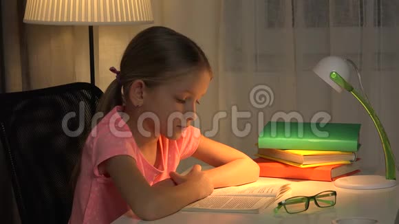 带眼镜的儿童读物在台灯学习的女孩4K视频的预览图