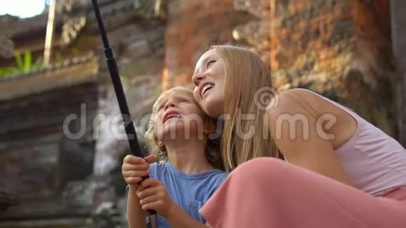 一位美丽的年轻女子和她的小儿子在楼梯上用动作台动作摄像机自拍的慢镜头视频的预览图