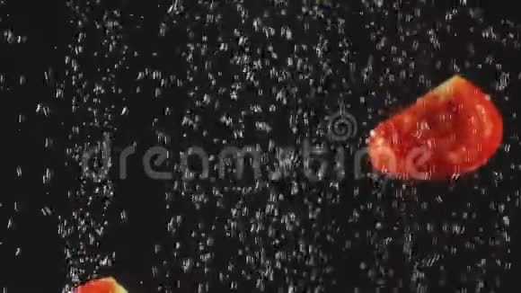 番茄片在黑色背景下落入水中新鲜蔬菜放在有气泡的水中有机食品健康视频的预览图