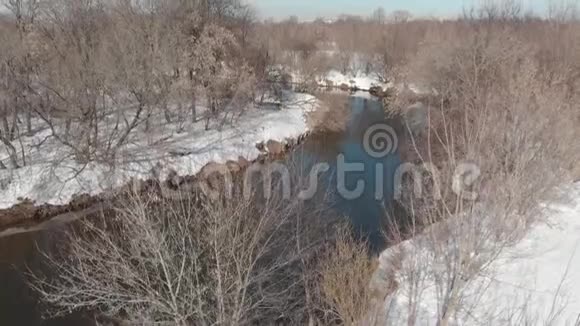 春天从河上的四架直升机上观看河水流淌在白雪和光秃秃的树木之间视频的预览图