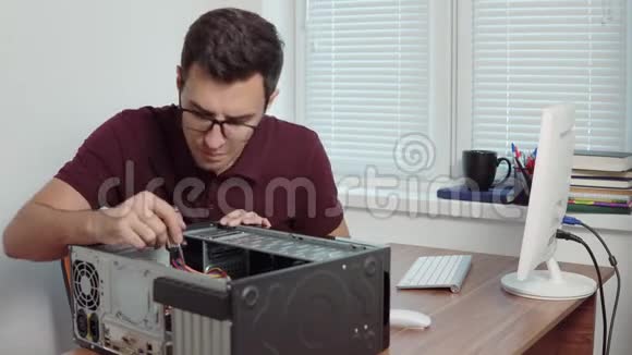 年轻的专业工人试图用螺丝刀修理办公室里的电脑并升级电脑硬件视频的预览图