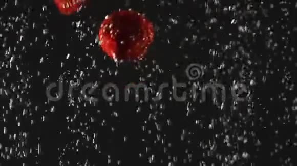 落下来的新鲜草莓溅到闪闪发光的水在黑色的背景关门视频的预览图