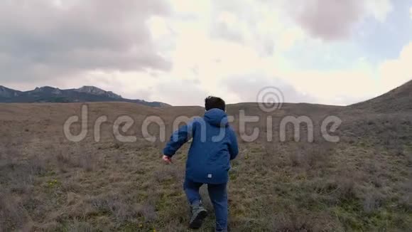一个开着黄花的男孩带着石头跑到地平线上慢动作视频视频的预览图