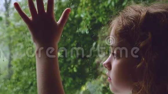 悲伤卷曲的小女孩望着雨落的窗外视频的预览图