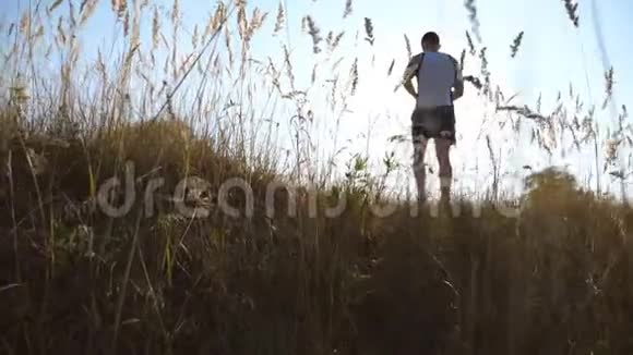 运动男孩在乡下散步年轻人走在夏天的田野上运动和积极的生活方式慢镜头视频的预览图