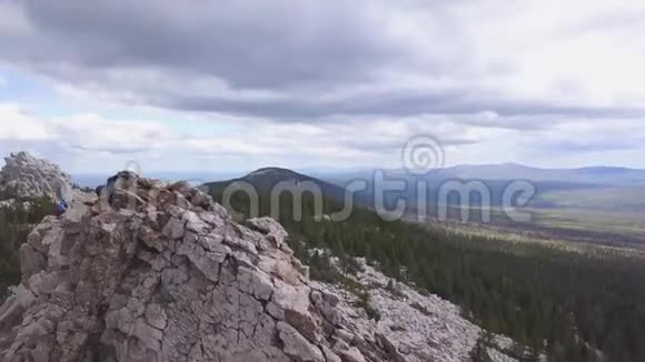 与游客一起俯瞰岩石剪辑多云天空的丘陵地形地平线游客攀登岩石悬崖的景色视频的预览图