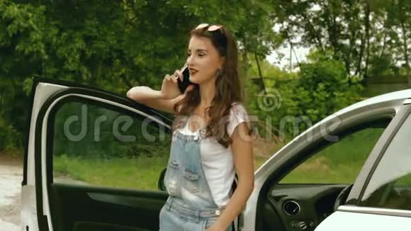 一位戴眼镜的时髦女士站在她的车旁边用手机说话视频的预览图