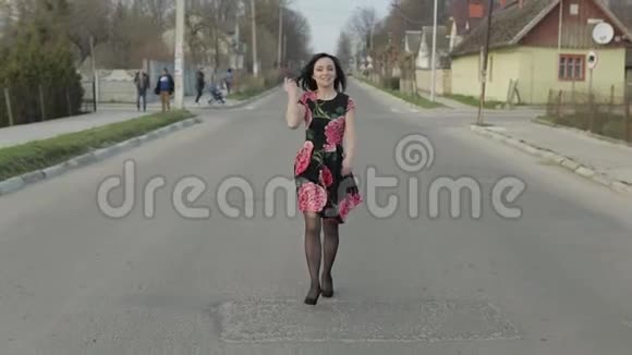 漂亮的年轻女子穿着一件带着鲜花走在公路上视频的预览图