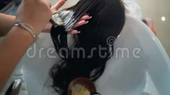在沙龙里的白种人女人用专业的化妆师做头发处理专业洗头按摩面膜视频的预览图