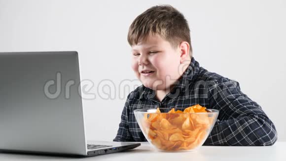 小胖男孩吃薯片用笔记本电脑看动画片视频的预览图