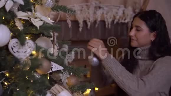 一个女孩装饰一棵圣诞树一个漂亮的球心情很好视频的预览图