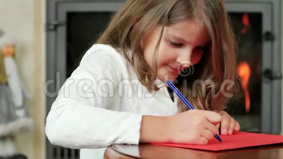 小女孩写字孩子在一张纸上画笔可爱的女孩坐在壁炉旁燃烧着火视频的预览图