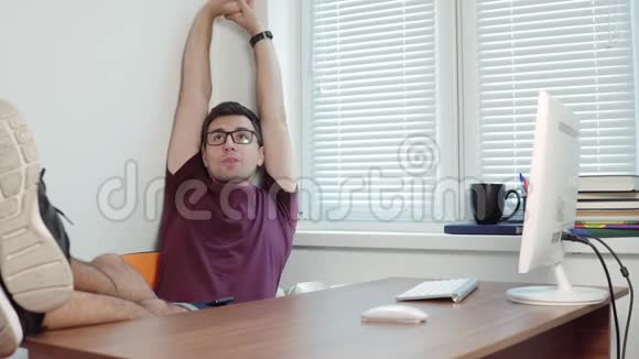 年轻的商人用电脑完成他的工作并在办公室里伸展手臂在办公室短暂休息4k视频的预览图