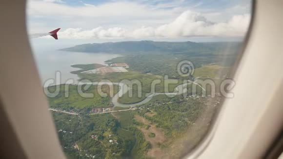 从一架飞行飞机的窗户俯瞰菲律宾岛屿在热带上空飞行时射击视频的预览图