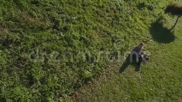 小女孩和她的狗坐在公园的草地上视频的预览图