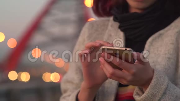 年轻漂亮的女孩晚上在城里用智能手机视频的预览图