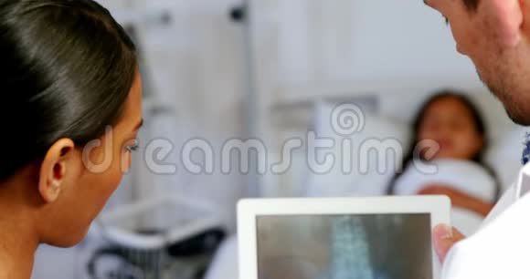 医生和护士看数字平板电脑的x光报告视频的预览图